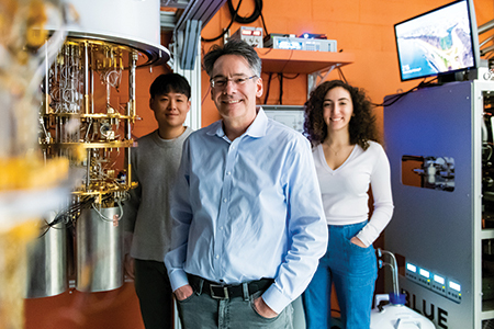 "Professor William Oliver stands in the center with postdoctoral candidates Hanlim "Harry" Kang to his left and doctoral candidate Aziza Almanakly to his right."